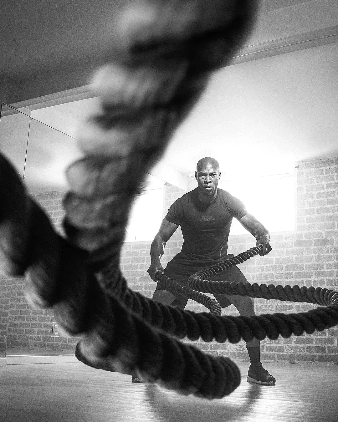 A man in stark, moody lighting mid-set on battle ropes