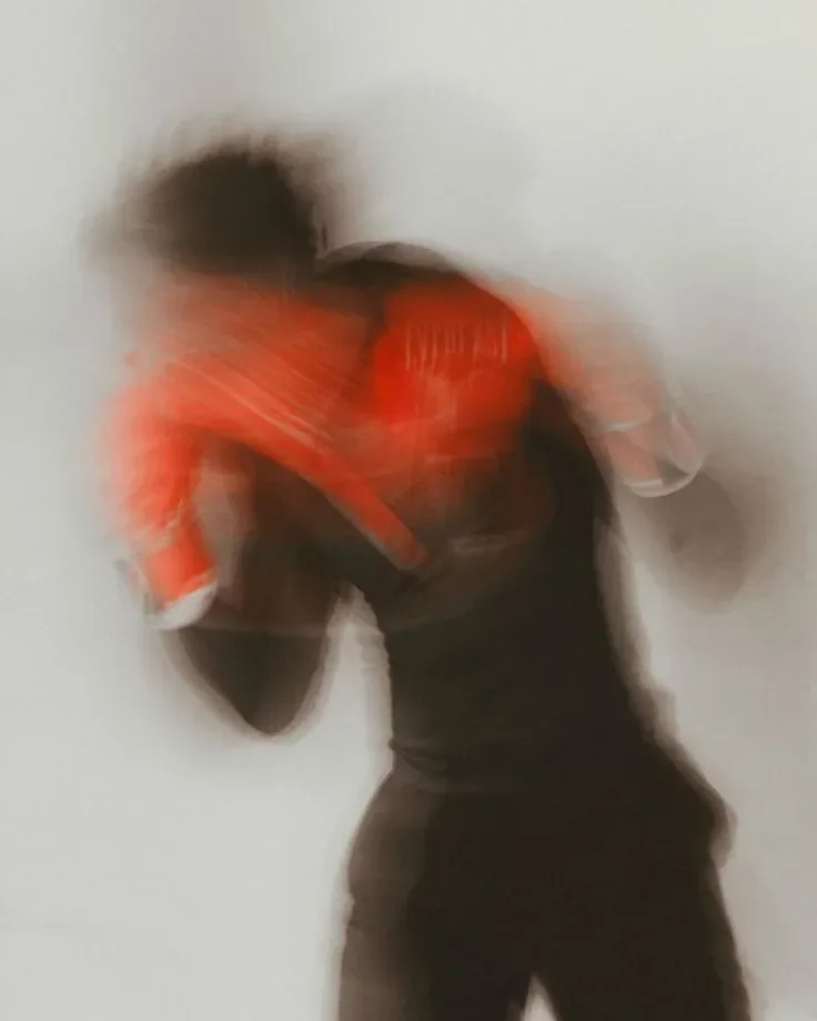 A long-exposure motion-blur photo of a strike, a single sharp hit of red on the glove against a pale background