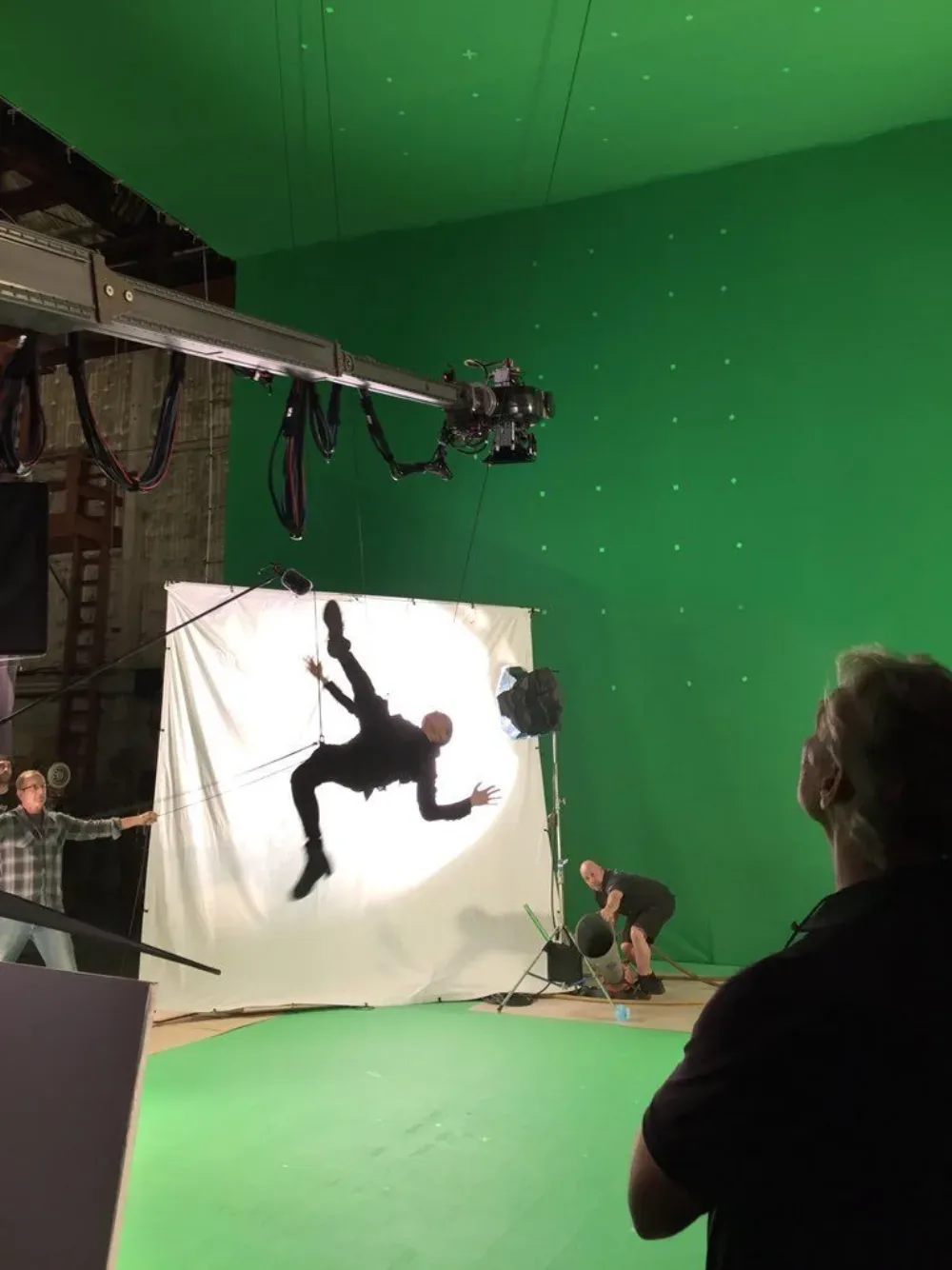 A stunt performer rigged on wires for a fall, shot against green screen